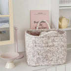 Taupe floral quilted storage basket with handles displayed on a shelf