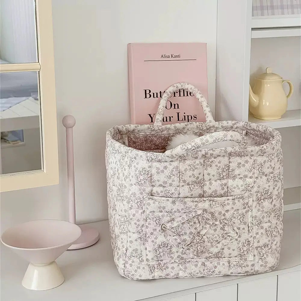 Taupe floral quilted storage basket with handles displayed on a shelf